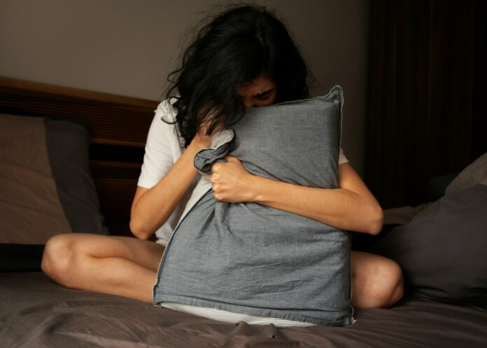 Photo by Solving Healthcare A woman sitting on a bed holding a pillow