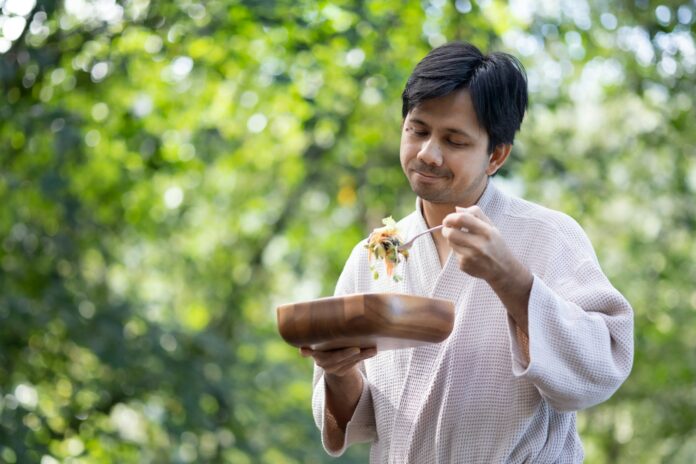 Photo by Supattra Khorasri a man holding a plate of food in his hands